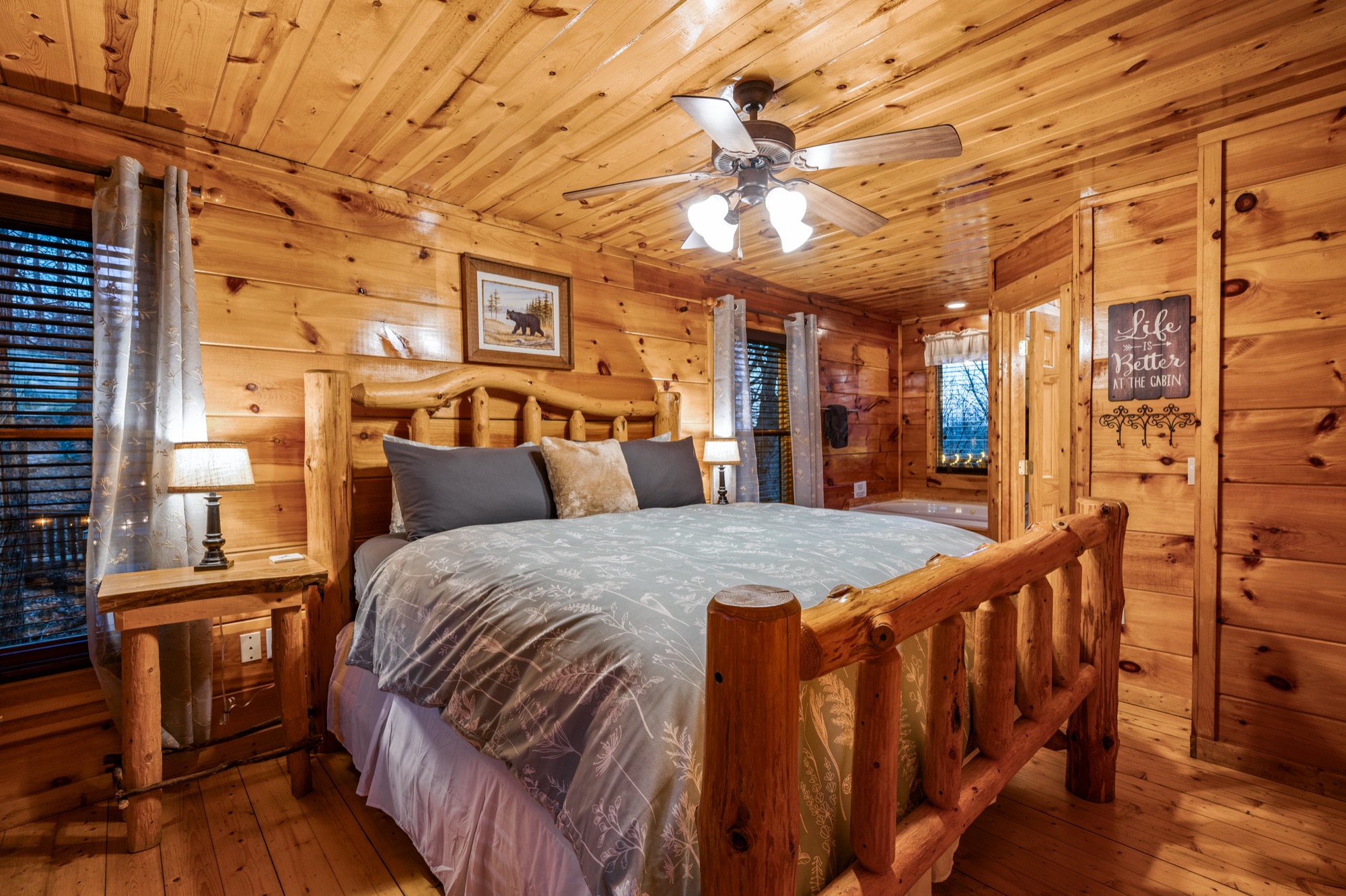 Primary bedroom at Bearadise with a log bed frame and a view through to the jacuzzi tub